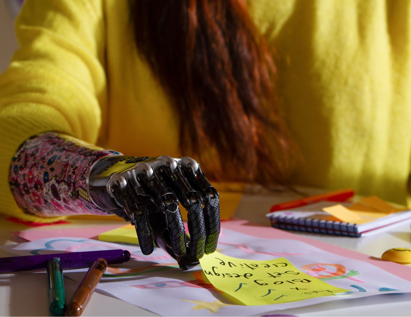 a person with a prosthetic hand sitting at a table with a sticky note
